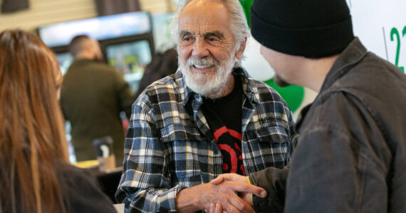 Tommy Chong shakes hands with Selena Morales and Elijah Harrison, both of Arlington, after taking a photo with them and giving them a couple signatures during 210 Cannabis Co’s grand opening in 2022 in Arlington, Washington. (Sound Publishing file photo)