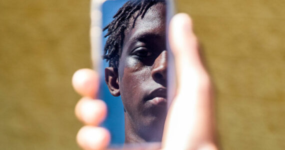 Jayden Hill, 15, an incoming sophomore at Monroe High School is reflected in the screen of a cellphone on Wednesday, July 10, 2024, in Monroe, Washington. Olivia Vanni/Sound Publishing