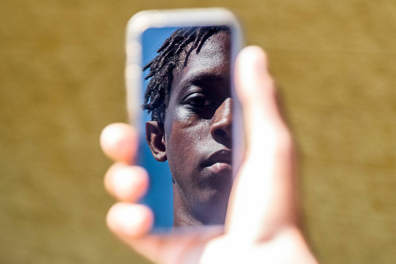 Jayden Hill, 15, an incoming sophomore at Monroe High School is reflected in the screen of a cellphone on Wednesday, July 10, 2024, in Monroe, Washington. Olivia Vanni/Sound Publishing