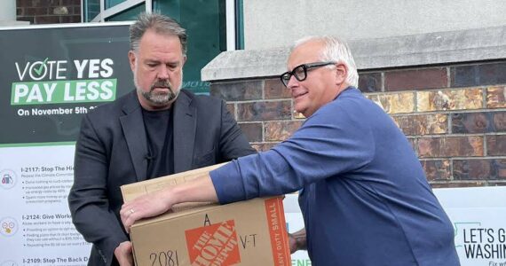 Brian Heywood, left, of Let’s Go Washington hands a box of signed Initiative 2066 petitions to Greg Lane, executive vice president of the Building Industry Association of Washington on July 2, 2024. (Jerry Cornfield/Washington State Standard)