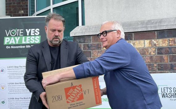 Brian Heywood, left, of Let’s Go Washington hands a box of signed Initiative 2066 petitions to Greg Lane, executive vice president of the Building Industry Association of Washington on July 2, 2024. (Jerry Cornfield/Washington State Standard)