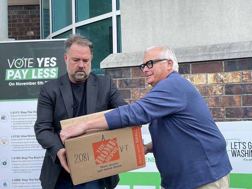 Brian Heywood, left, of Let’s Go Washington hands a box of signed Initiative 2066 petitions to Greg Lane, executive vice president of the Building Industry Association of Washington on July 2, 2024. (Jerry Cornfield/Washington State Standard)