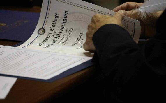 One of Washington’s 12 Democratic electors uses a feather pen to fill out the documents to cast their Electoral College vote for Kamala Harris and Tim Walz. Harris lost to Republican President-elect Donald Trump, but won a majority of Washington’s votes in the November election. (Courtesy of Washington State Archives)