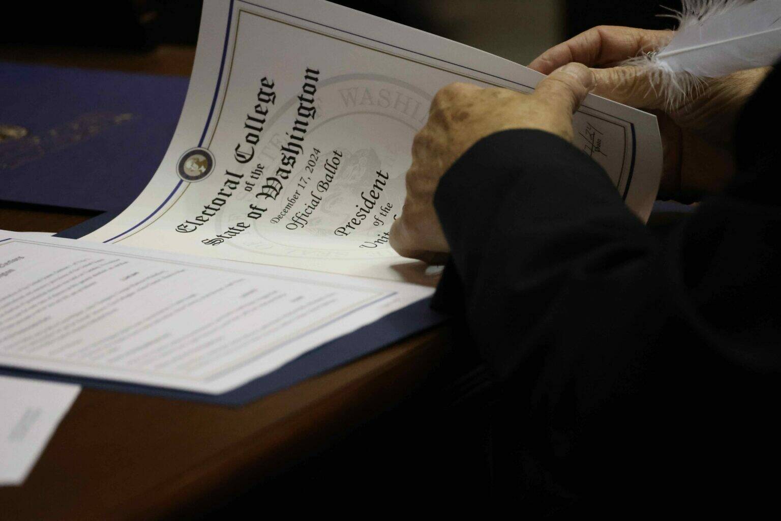 One of Washington’s 12 Democratic electors uses a feather pen to fill out the documents to cast their Electoral College vote for Kamala Harris and Tim Walz. Harris lost to Republican President-elect Donald Trump, but won a majority of Washington’s votes in the November election. (Courtesy of Washington State Archives)