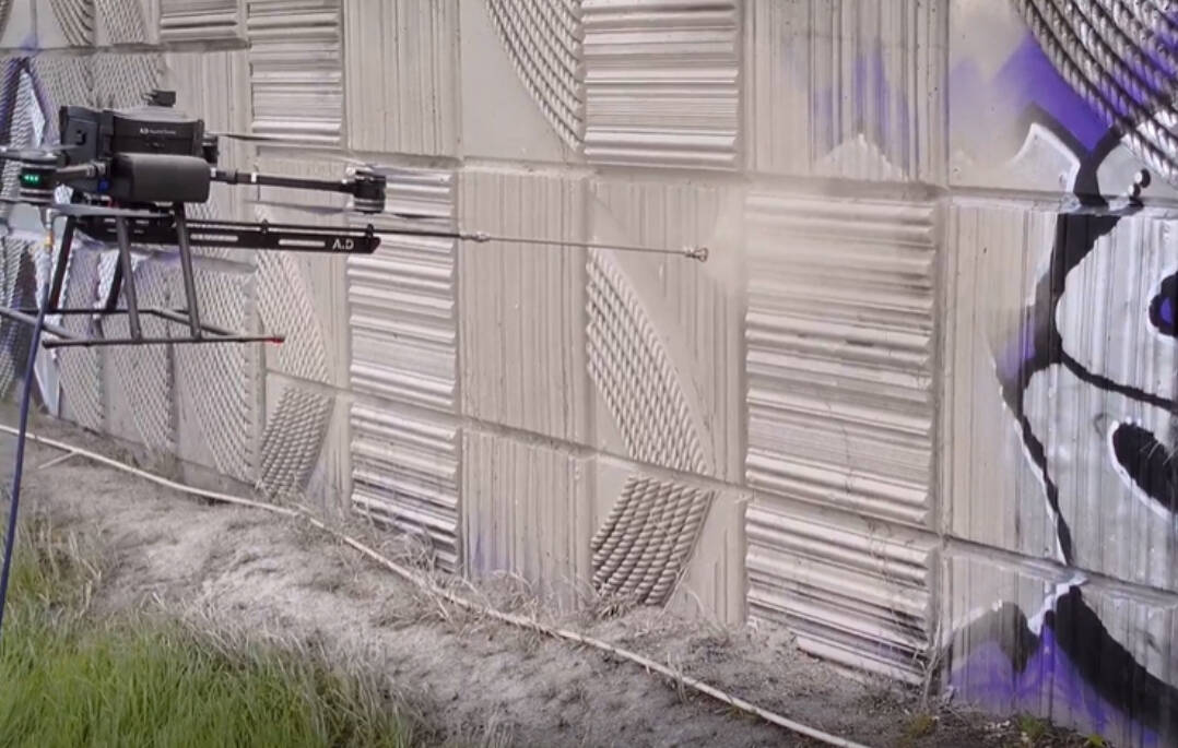 A prototype drone test sprays paint to cover up graffiti in Tacoma earlier this spring. (Courtesy of the Washington State Department of Transportation)